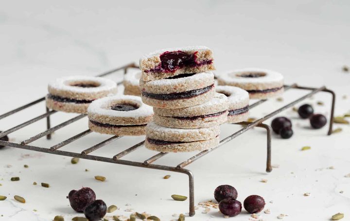 Raw vegan Linzer cookies on a baking rack on a white table